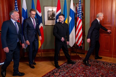Zelenskiy and fellow leaders walk through a room with multiple national flags in Oslo