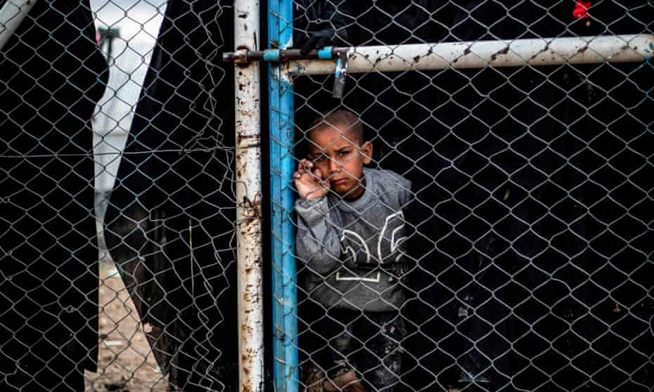 A child behind a wire fence door in al-Hawl camp in Syria, which houses relatives of Islamic State fighters, including Australians.