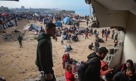 Palestinian people gather with their belongings near a roadblock on al Rashid Street in central Gaza.