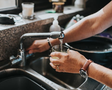 Person at a tap, filling a glass of water.
