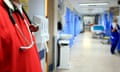 a medic in a red tunic with a stethoscope in the foreground as the picture pans out on to a largely empty hospital corridor