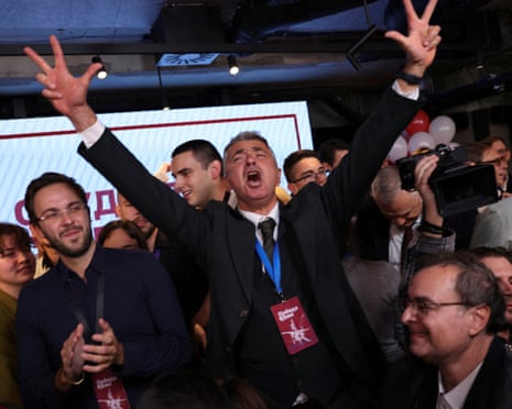 Ilija Srdanovic raises both arms making peace signs, celebrating election results amid a crowd