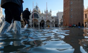 Tourists walk in the flooded St Mark’s Square
