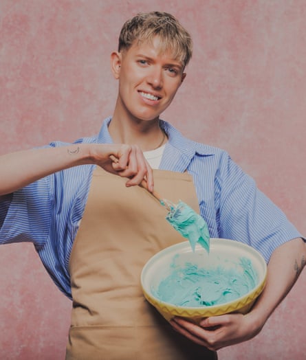 A blond young man mixes blue batter in a bowl.