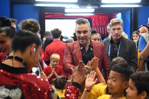 Robbie greets mascots following his performance in the opening ceremony
