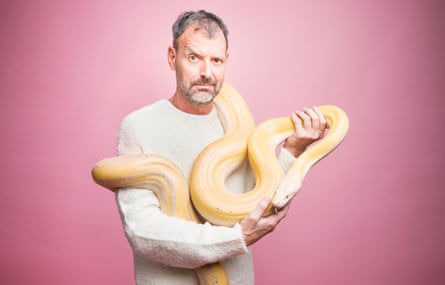 Tim Dowling holding a long snake, against pink background