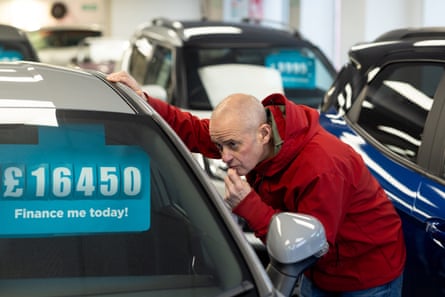 Mature male shopping for a car inside a car dealership showroom
