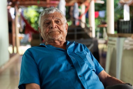 An older man with white hair, wearing a blue shirt