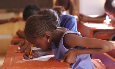 African pupils sitting at their wooden desk in the classroom.