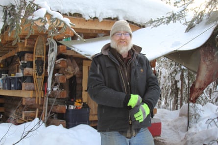 Glenn Helkenn outside his small log cabin on the outskirts of Fairbanks.