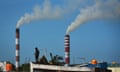 A man stands on the roof of a building as smoke billows from the chimney of a power plant at Ennore near Chennai, India, on 8 October 2021 
