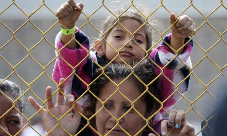 Daniela Fernanda Portillo Burgos sits on the shoulders of her mother, Iris Jamilet, 39, as they look out through the fence of a immigrant shelter in Piedras Negras.
