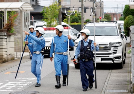 Police officers with sticks walk down a busy road