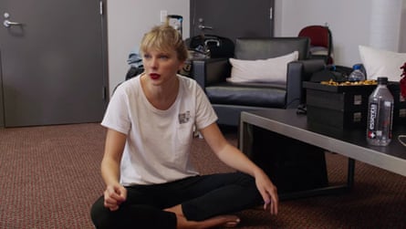 A young woman sits on the floor of a hotel room cross legged