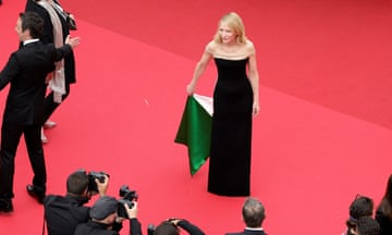 blanchett in black dress, holding up part of it to show green and very light pink