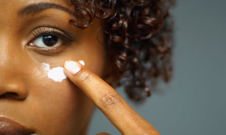 Woman applying cream to her cheek