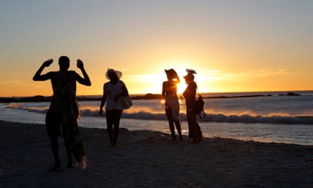 Beach goers are silhoutted against the sun as its sets for the last time for 2014 in Camps Bay, Cape Town, South Africa, 31 December 2014.