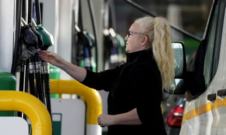 A woman refuel her car at a petrol station in London.