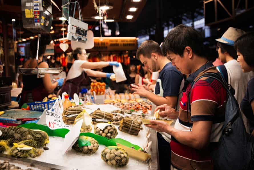 Tourists sampling food at Barcelona’s Boqueria Market.