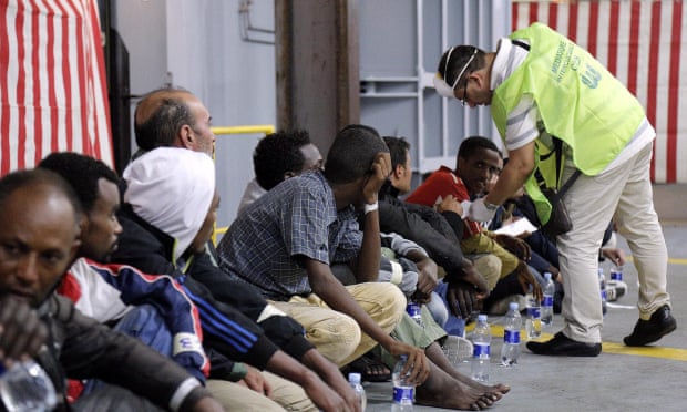 A doctor checks migrants aboard the Mare Nostrum after being rescued 25 miles off Italy.