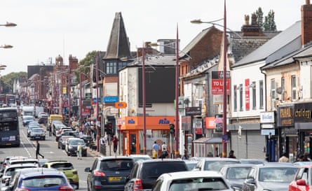 View up a busy road with shops on one side.