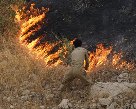 A man works to control the spread of a fire that has scorched the ground.