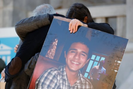 people embrace behind poster of smiling man