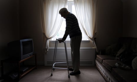 Profile of an unhappy-looking elderly man standing by a window and holding a walking frame