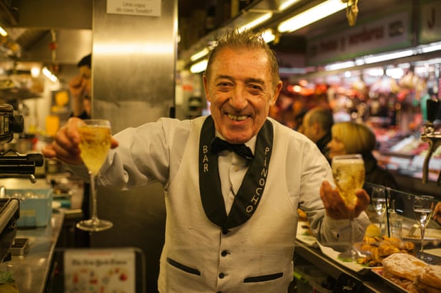 Bartender Juanito holding two cava glasses in the Boqueria Market in Barcelona