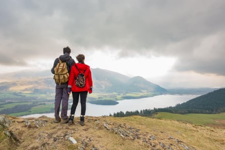 Two walkers looking at the view of Bassenthwaite Lake and the Skiddaw range from Sale Fell, Lake District