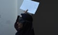 Woman wearing a blindfold and holding a piece of paper in the air.