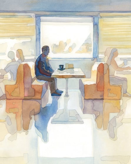 a man sitting alone in a diner; the other booths are filled with people eating together