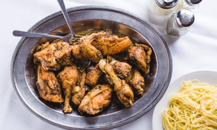 Dish of chicken legs and thighs in a metal dish, next to a bowl of spaghetti, from Mosca's, New Orleans, US.