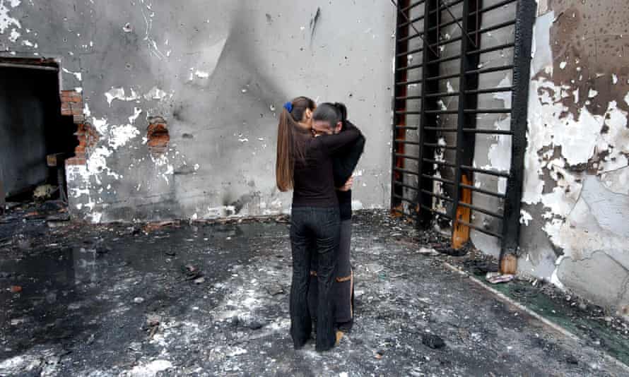 Two girls hug in the destroyed school gym in Beslan.