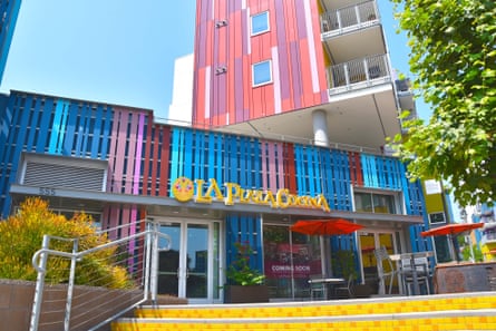 A brightly colored building front, painted in stripes of blue, pink and red, stands in contrast to the yellow stairs in front of it.