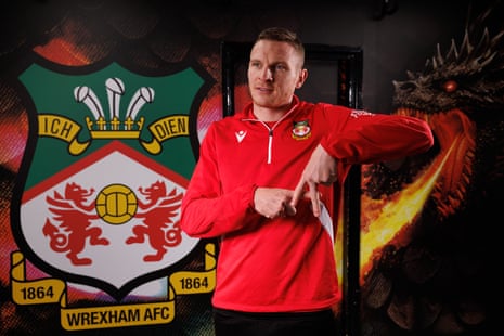 Paul Mullin poses in front of a Wrexham badge.