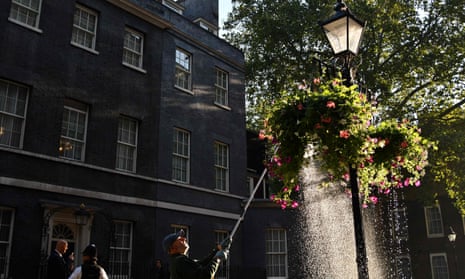 A gardener watering a hanging basket of flowers outside 10 Downing Street in 2020.