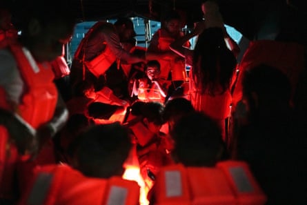 a boy looks out from among many people wearing orange life jackets