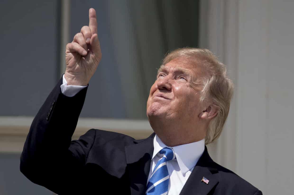 In this Aug. 21, 2017, file photo, President Donald Trump points to the sun as he arrives to view the solar eclipse at the White House in Washington.