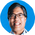 man in glasses and button-down smiling against blue background