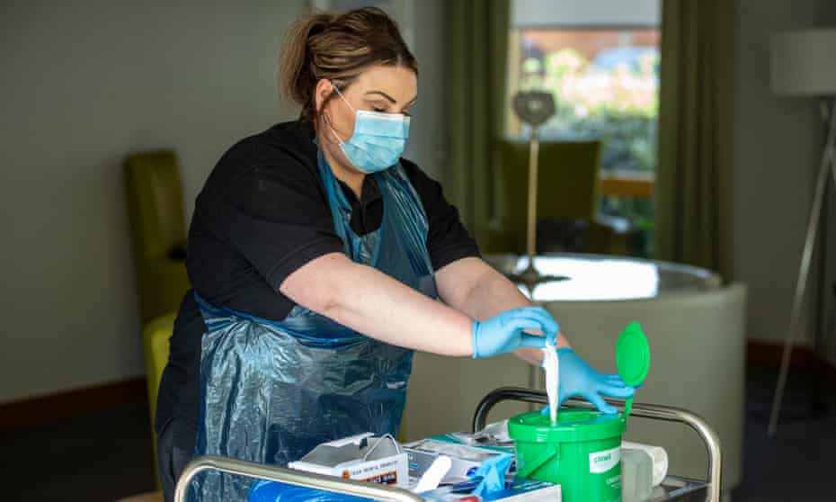 Megan Watt senior social care worker dons PPE as part of the new Coronavirus precautions. David Walker Gardens Care Home run by South Lanarkshire Health and Social Care Partnership. THESE PHOTOGRAPHS WERE TAKEN WITHOUT ENTERING INSIDE THE CARE HOME -BY PHOTOGRAPHING THROUGH CLOSED WIDOWS OR AT A DISTANCE THRU OPEN FRENCH WINDOWS WHILST AT A SAFE DISTANCE IN THE GARDEN - WITH THE PRIOR CONSENT OF SERVICE USERS, CARE HOME MANAGEMENT AND SOUTH LANARKSHIRE COUNCIL