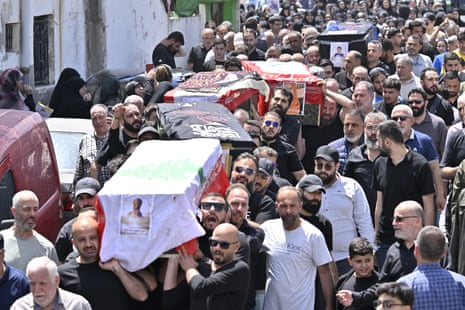 Mourners filled a street, walking alongside individuals carrying six coffins.