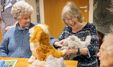 Agnes Forgie and Marjorie Stephenson stroke a robot cat at Oak Manor care home