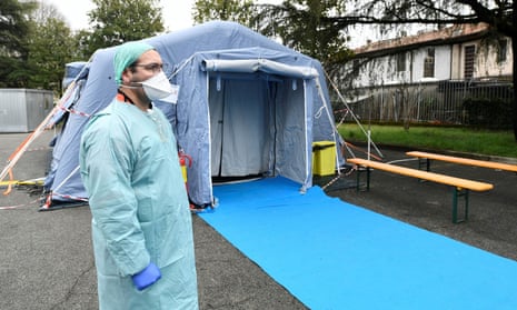 A medical worker waits by a coronavirus checkpoint at the entrance of the Spedali Civili hospital in Brescia, Italy.
