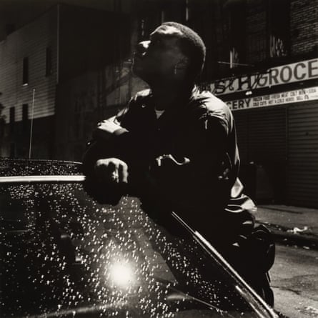 A man leaning on a car and looking up