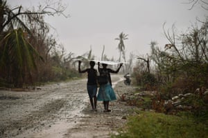 Women walk protecting themselves from rain in the commune of Chadonyer, Haiti