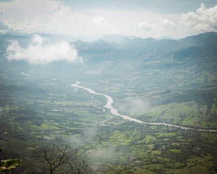 A view from a hill of a river winding through a lush green valley