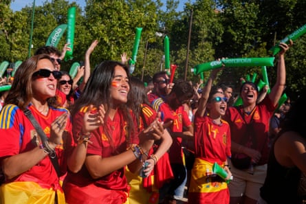 People in Madrid, wearing red t-shirts, watching the final between England and Spain on a big screen in a park