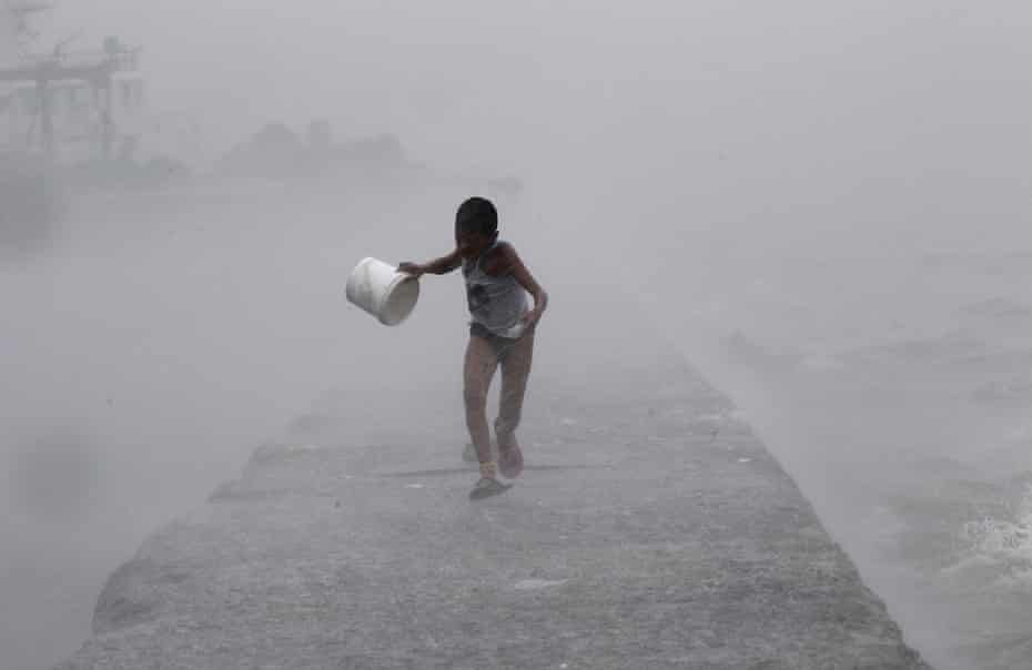 A boy runs as heavy rains and high waves crash around him