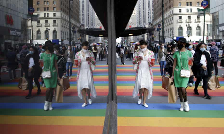 Pedestrians walk on the sidewalk covered in the colors of the rainbow in New York City in March 2021.